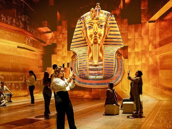 Woman in Egyptian queen costume posing against hieroglyphic background