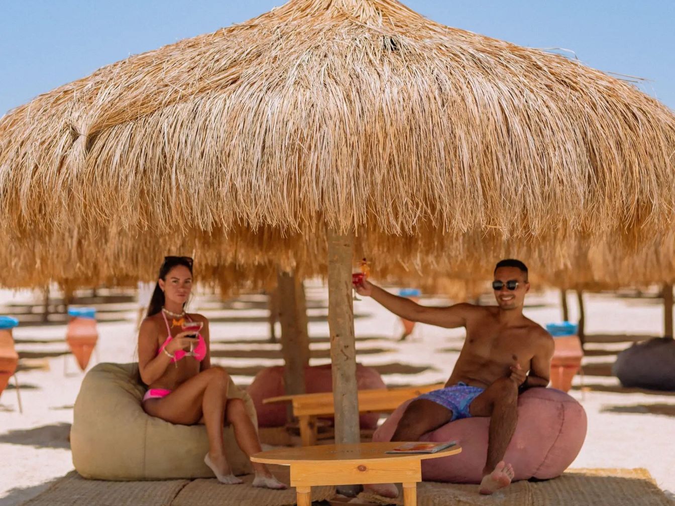 Guests relaxing on bean bags under beach umbrellas