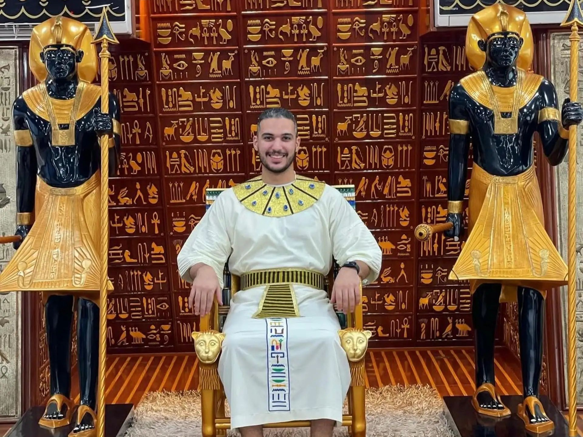 Man sitting on a Pharaonic throne between two Egyptian statues