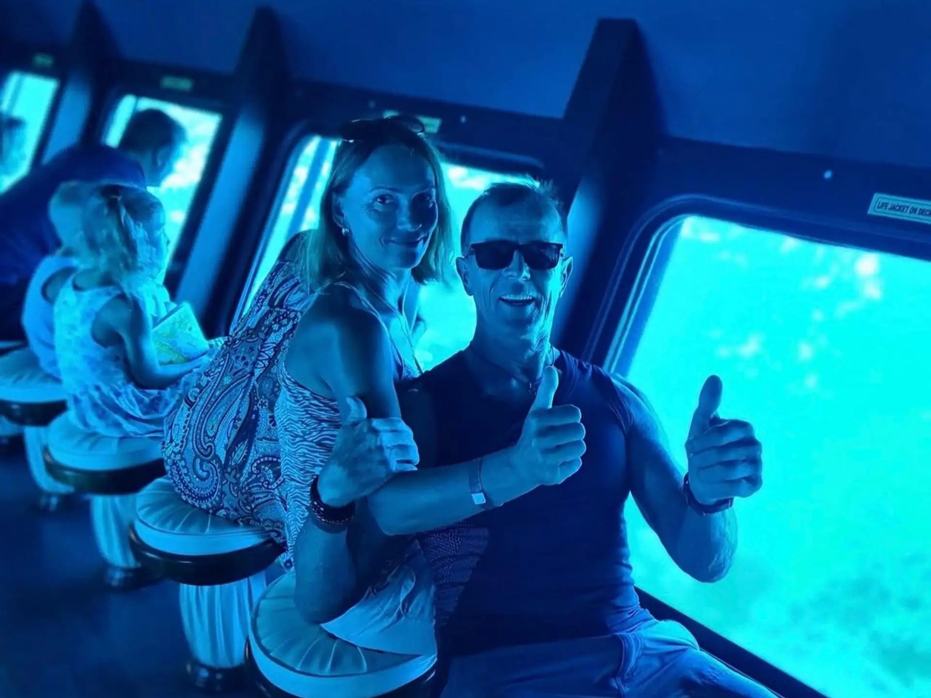Passengers looking through large underwater windows at the sea floor