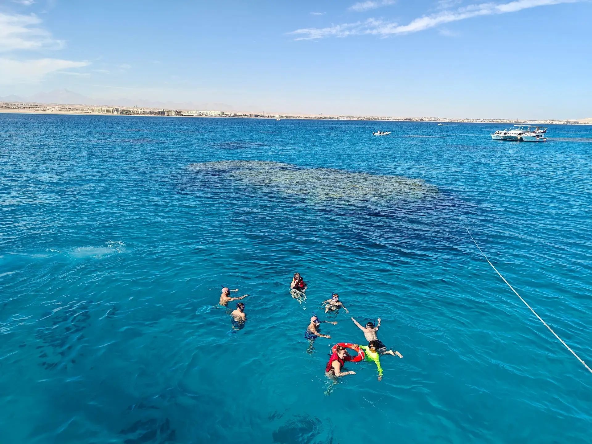 Group of people snorkeling in clear blue water next to the reef