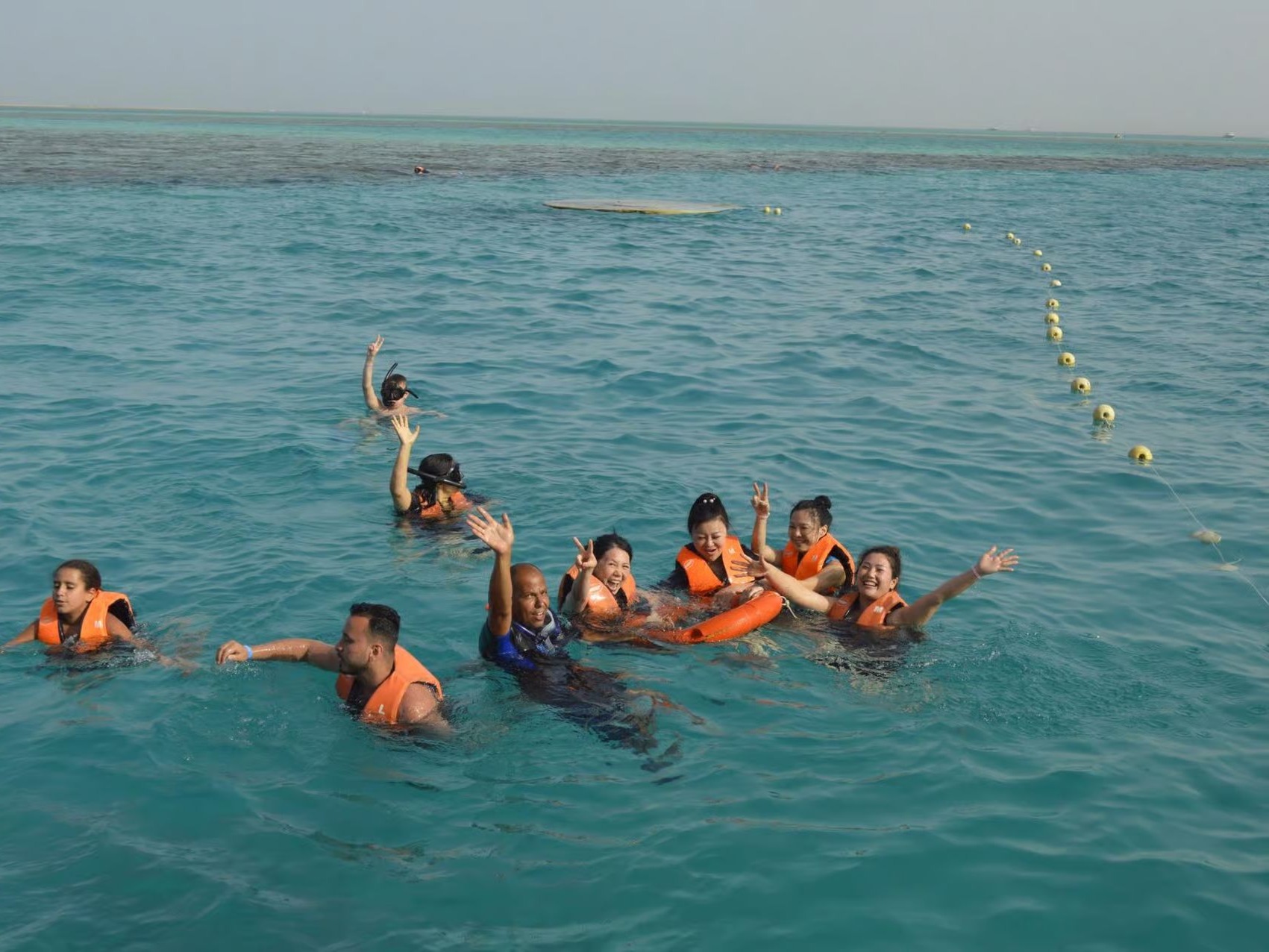 Touristen mit Schwimmwesten winken beim Schwimmen im Meer