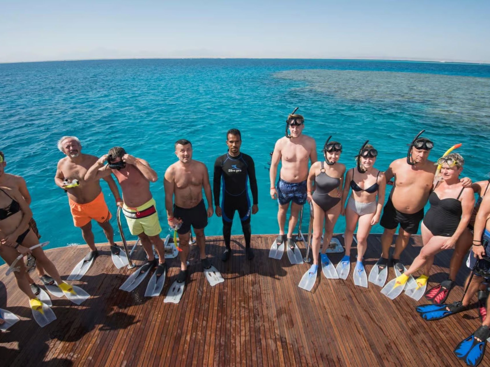Group of snorkelers standing on a boat ready to enter the water